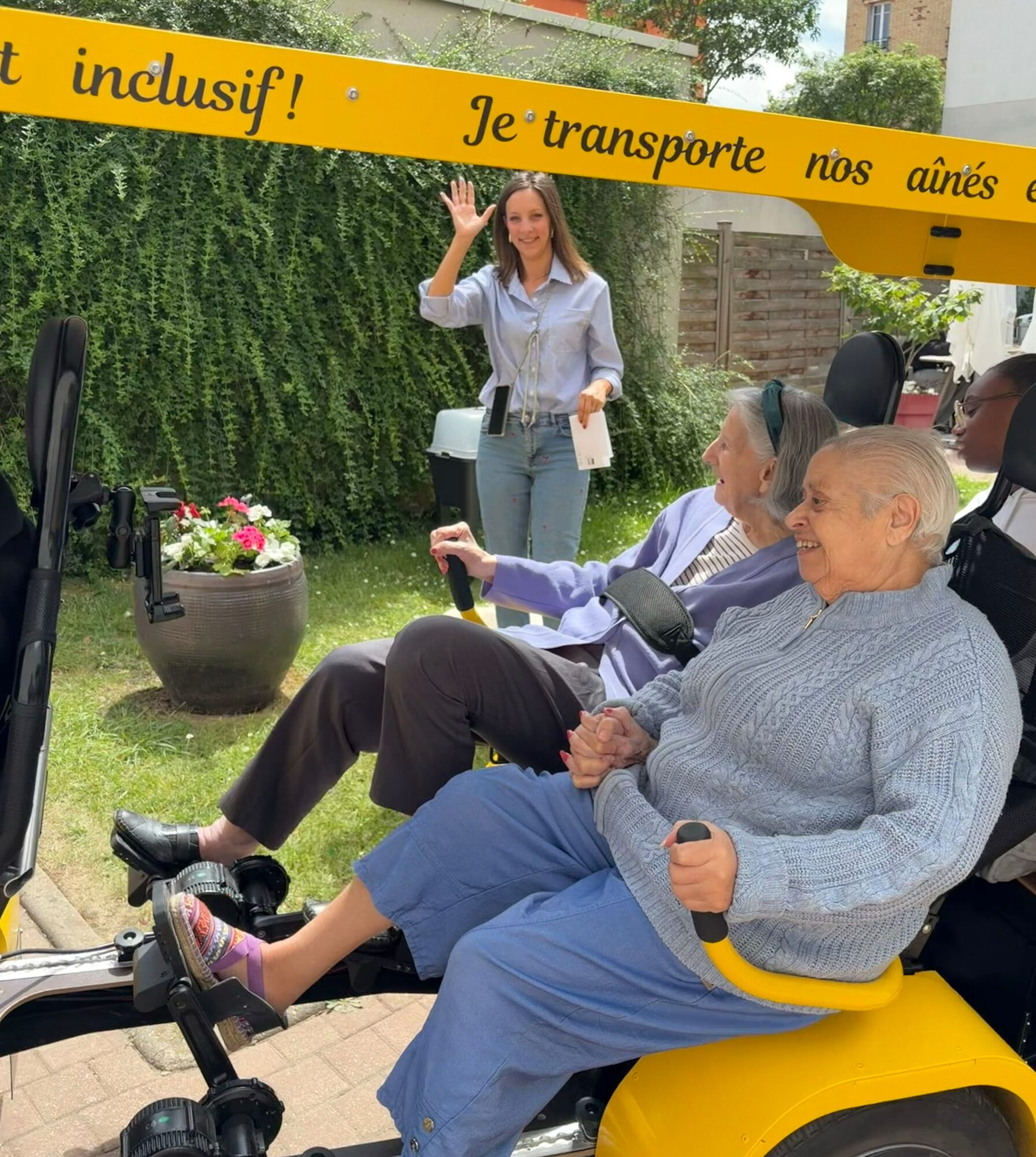 À bord du OuiCycle : deux résidentes souriantes et une animatrice qui salue lors d’une sortie.