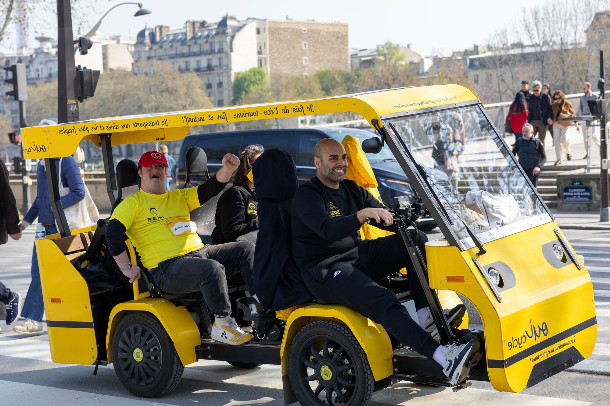 Le OuiCycle en sortie dans la ville : le conducteur-animateur souriant et des passagers à bord.