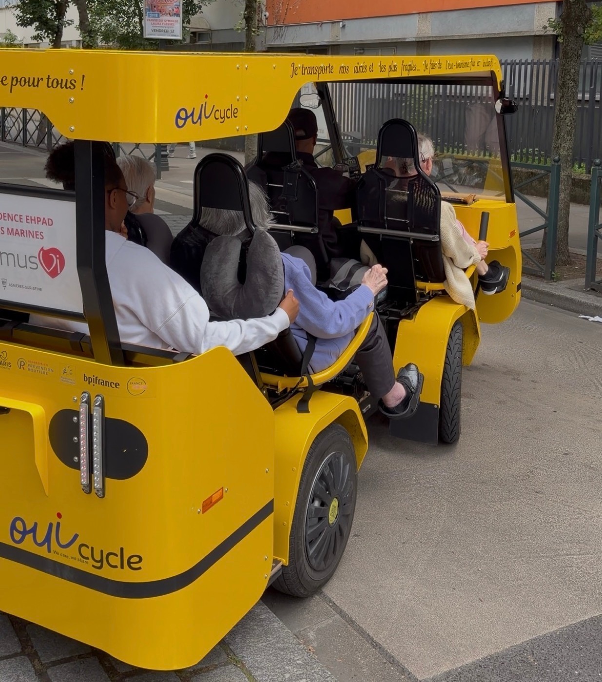Le OuiCycle chargé de résidents et de son conducteur-animateur, prêt à partir dans la rue.