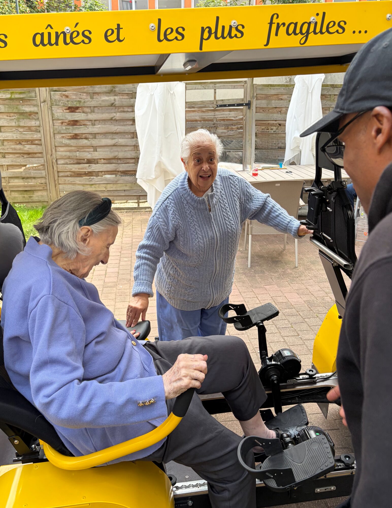 Une résidente souriante installée à bord du OuiCycle lors d'une sortie en extérieur.