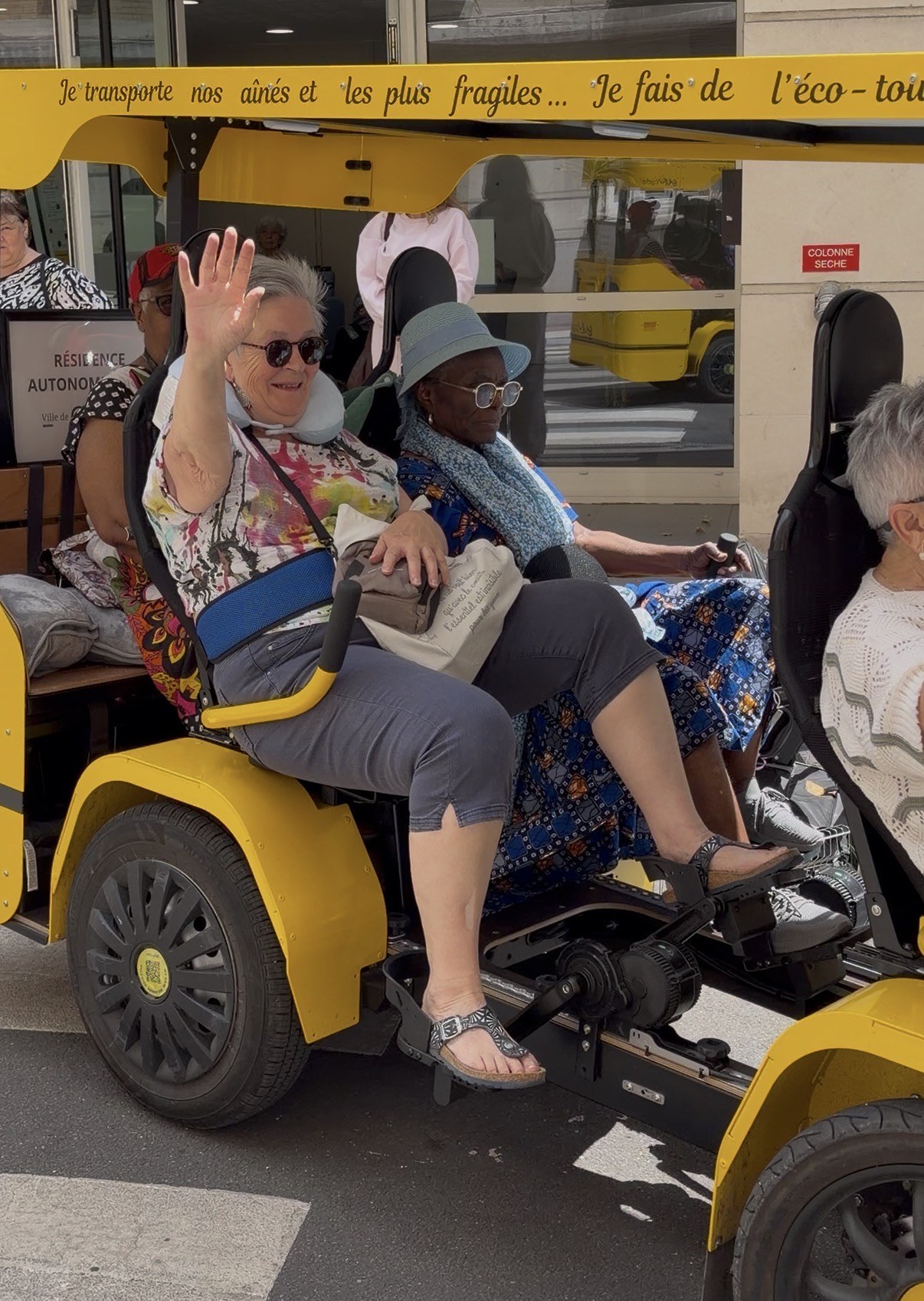 Deux résidentes de résidence autonomie côte à côte à bord du OuiCycle, complices et souriantes.